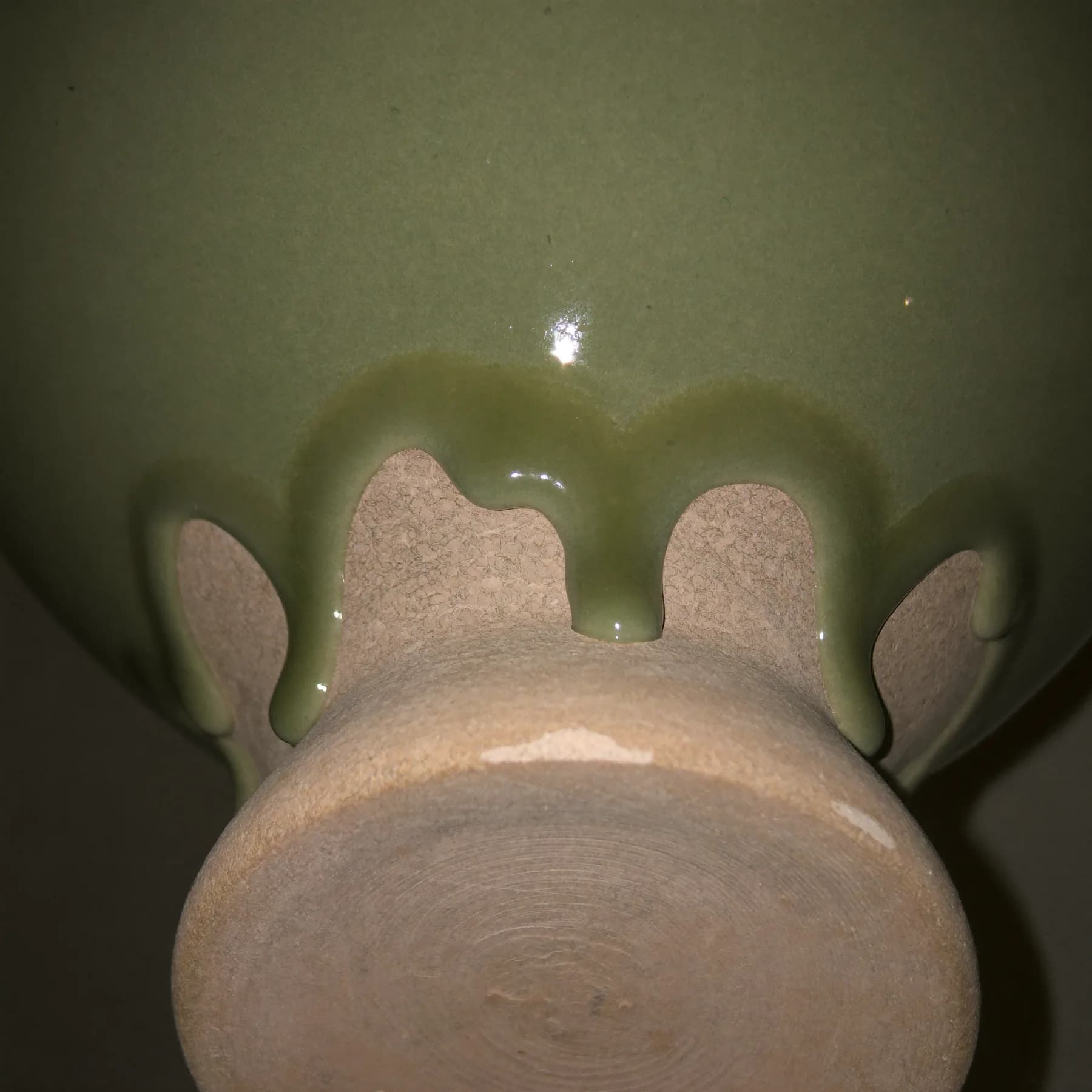 Celadon glaze pooling above a bare clay foot