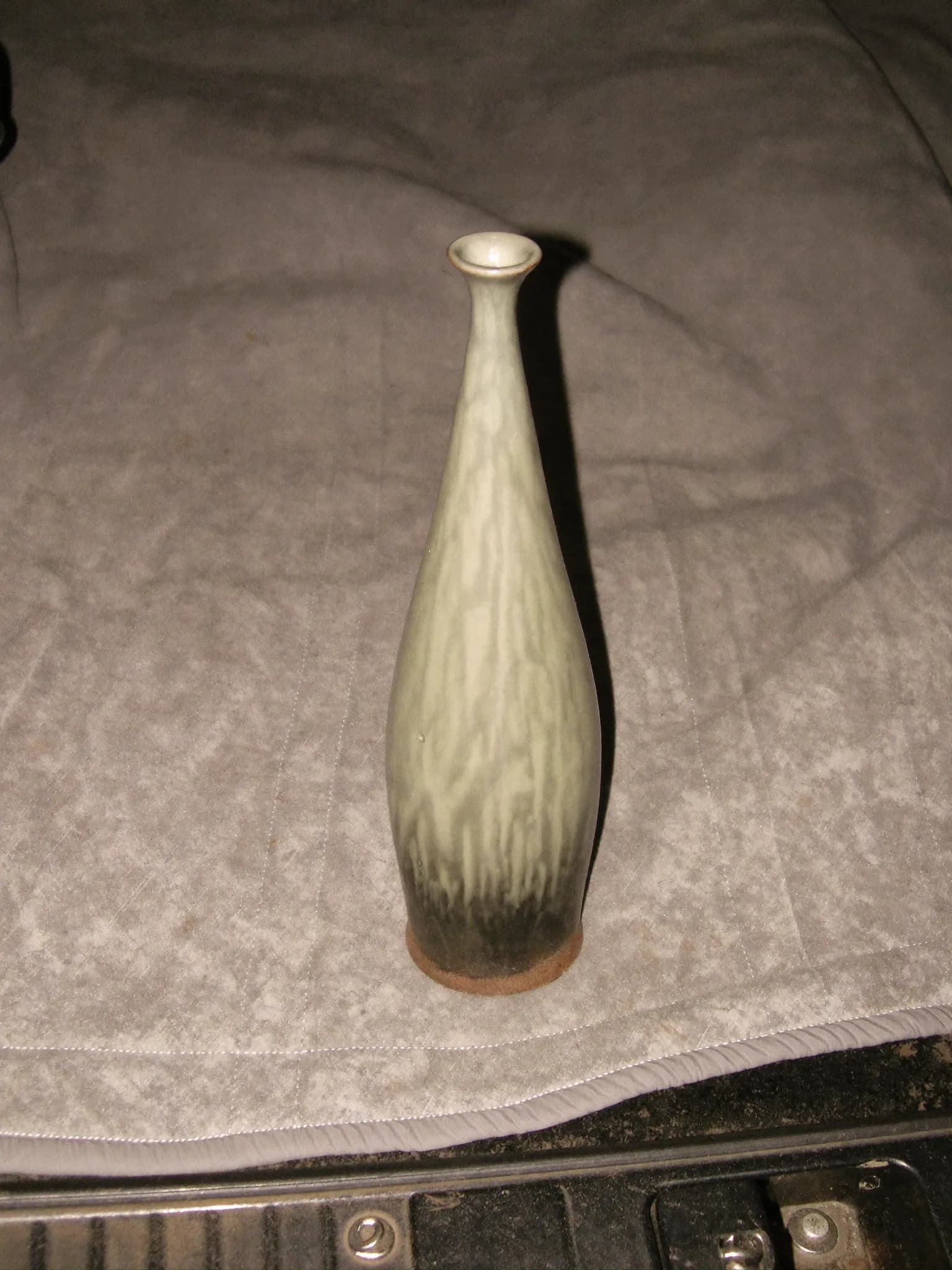 A small sage-green stoneware bud vase with a narrow neck